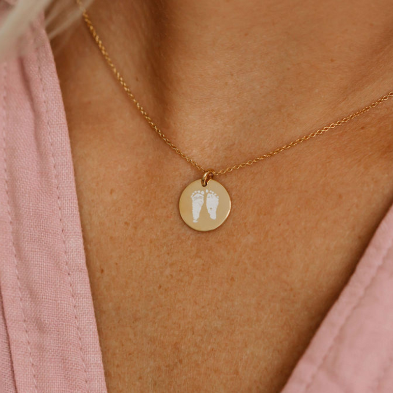 gold footprint necklace with white laser engraving 