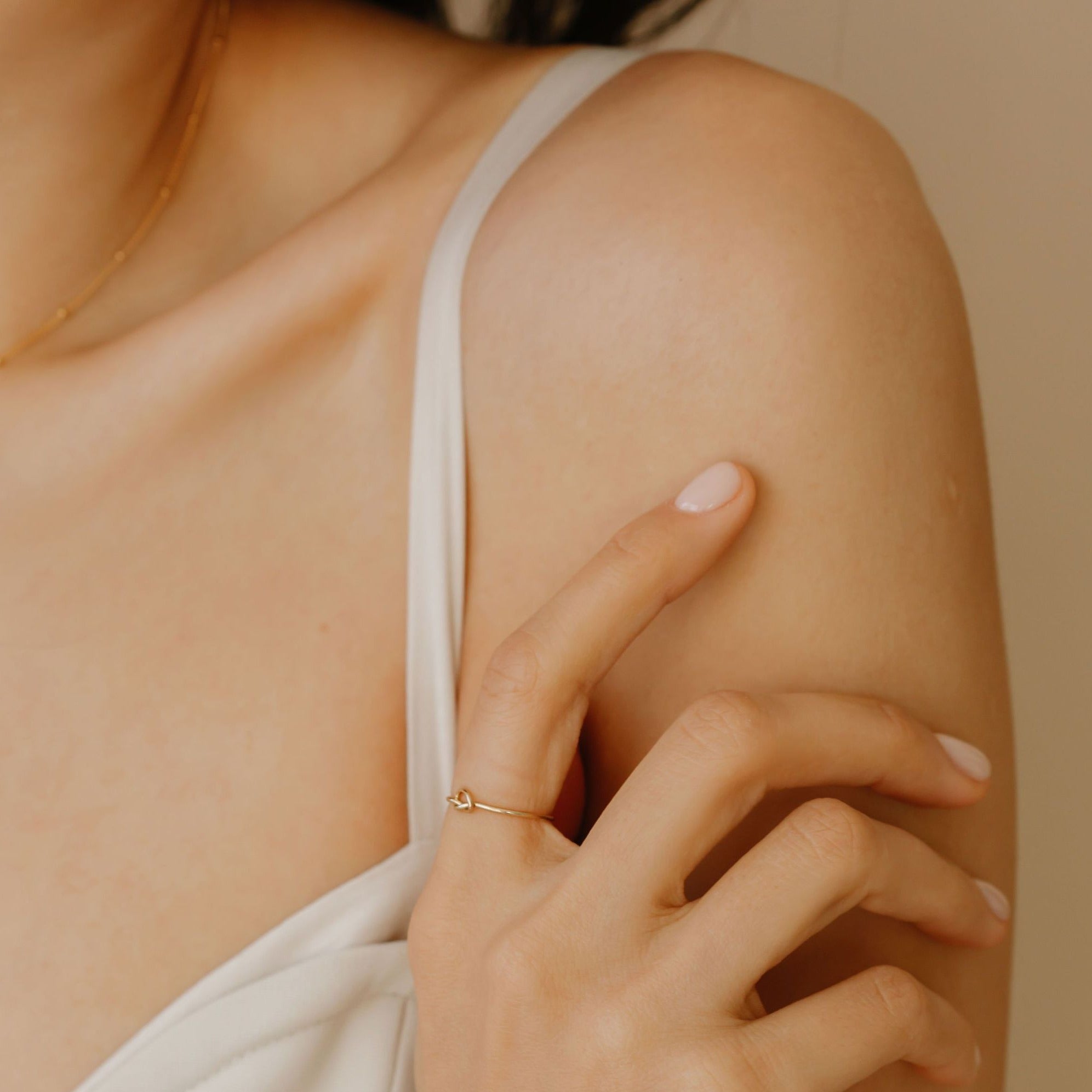 a woman is wearing a dainty gold knot handmade ring 