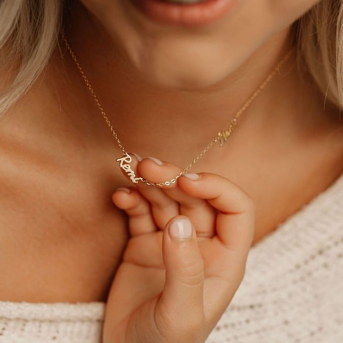 child reaching for her name on her mom name necklace