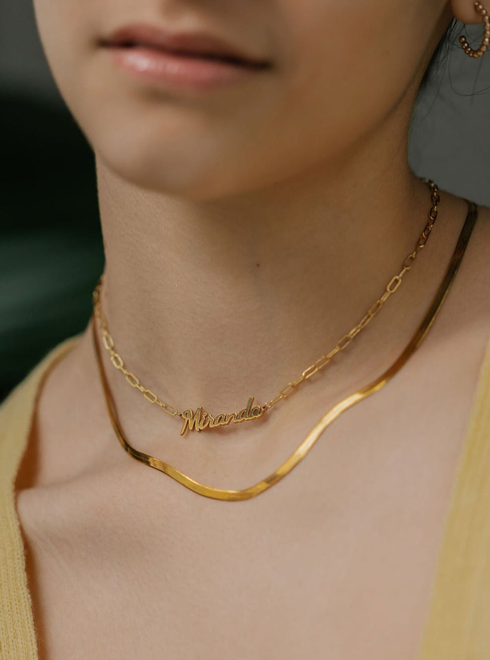 a woman is wearing bold name necklace with link chains