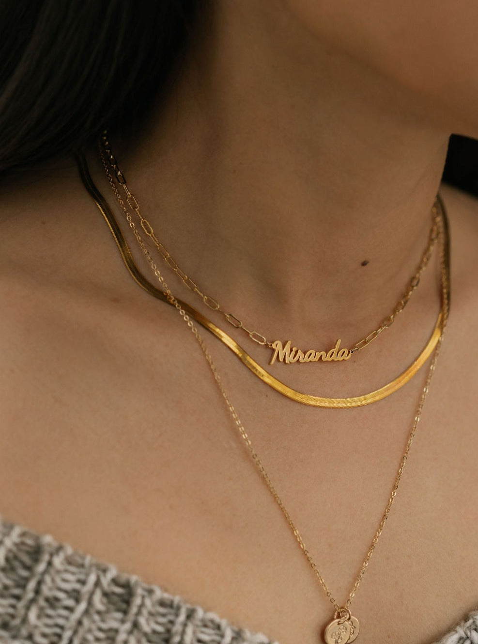 a woman is wearing 3 layered necklaces. Name necklace with gold herringbone necklace made in Canada