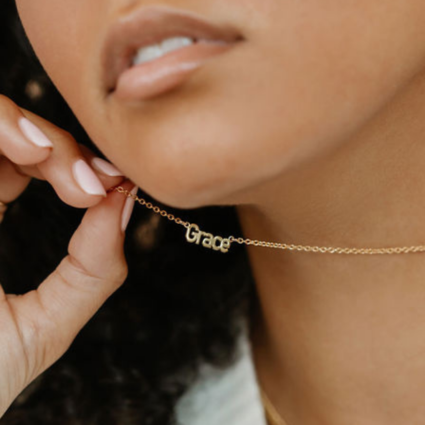 a woman is wearing a name necklace