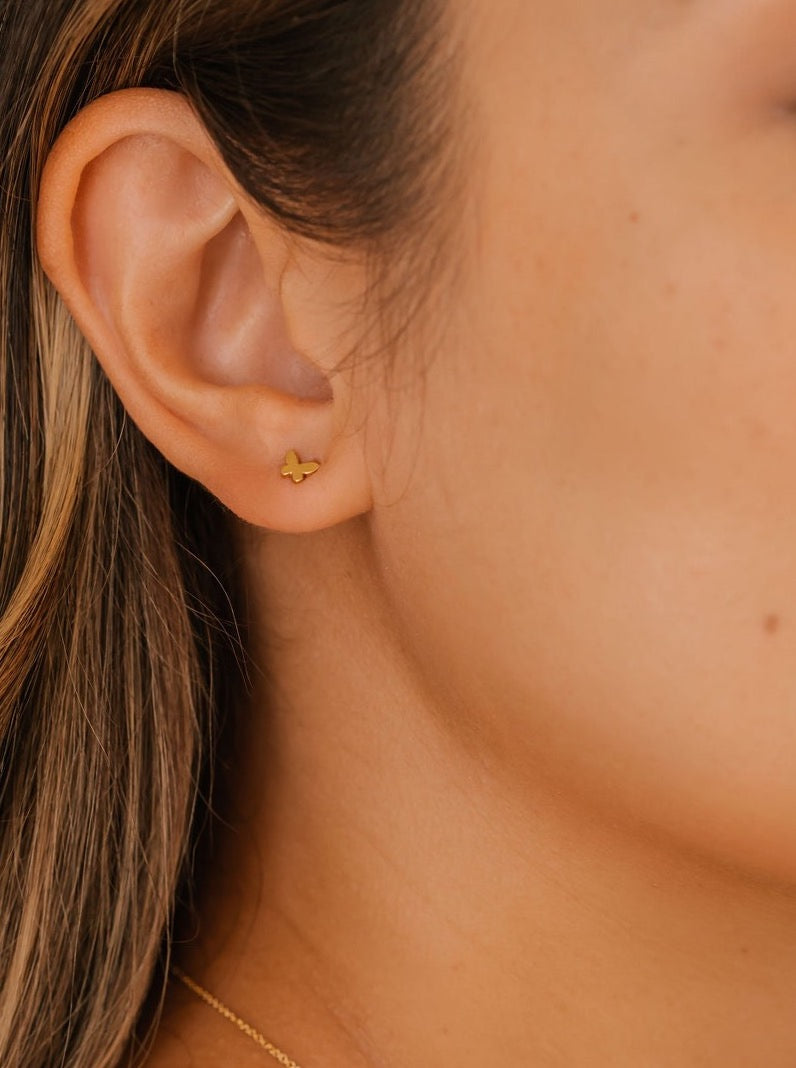 a woman is wearing butterfly stud earrings made in Edmonton, AB, Canada