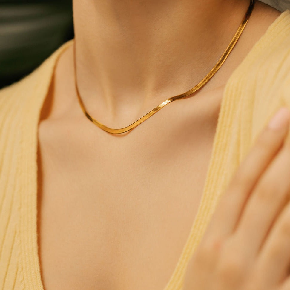 a woman is wearing gold vermeil herringbone necklace made in Canada. 