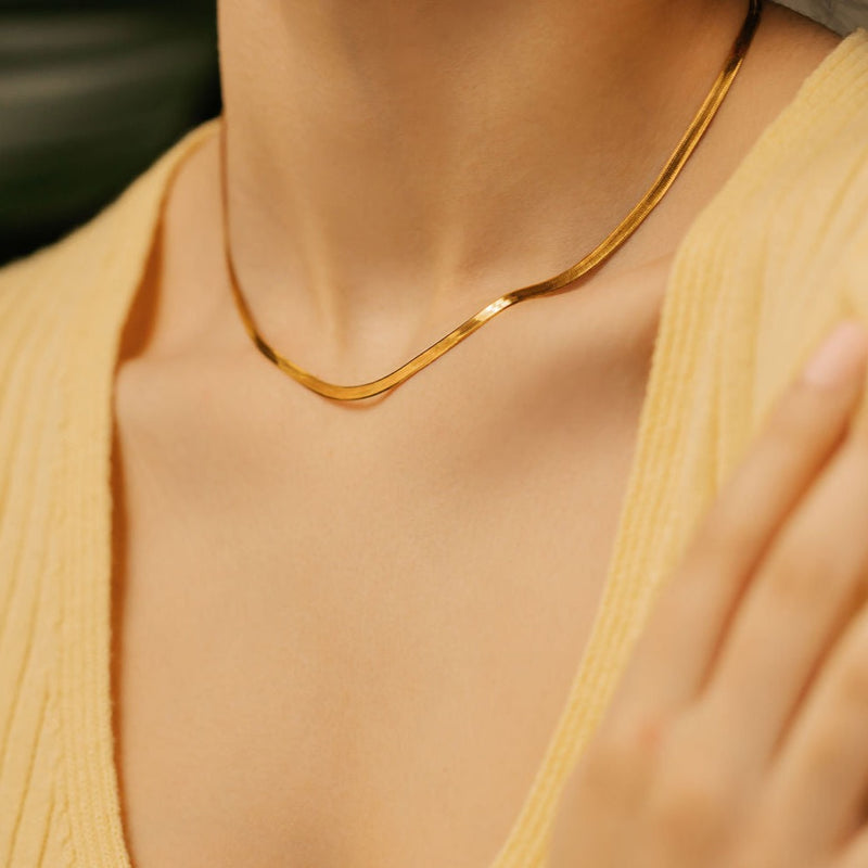 a woman is wearing gold vermeil herringbone necklace made in Canada. 