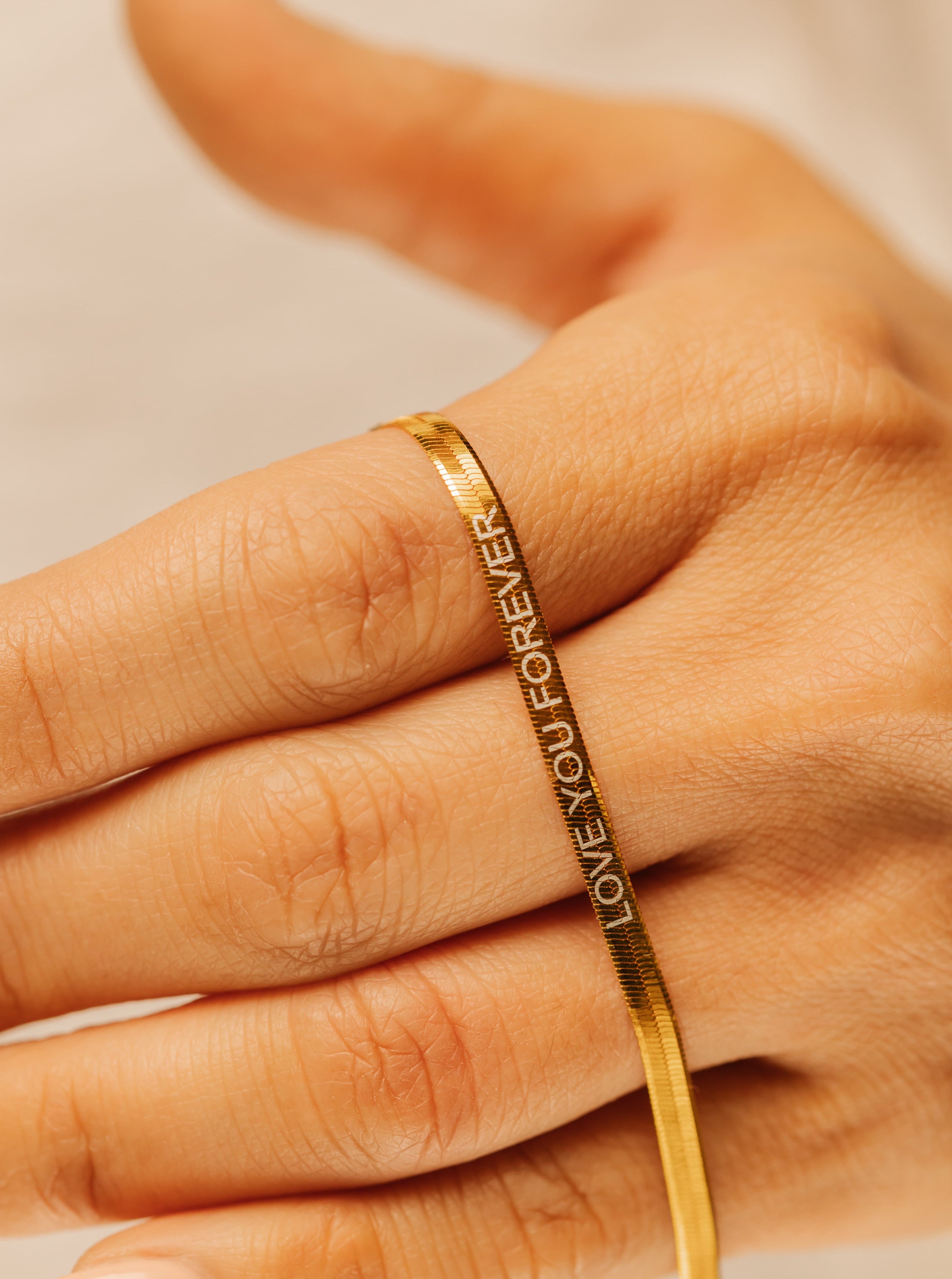 A woman is holding the gold vermeil herringbone engraved chain necklace 