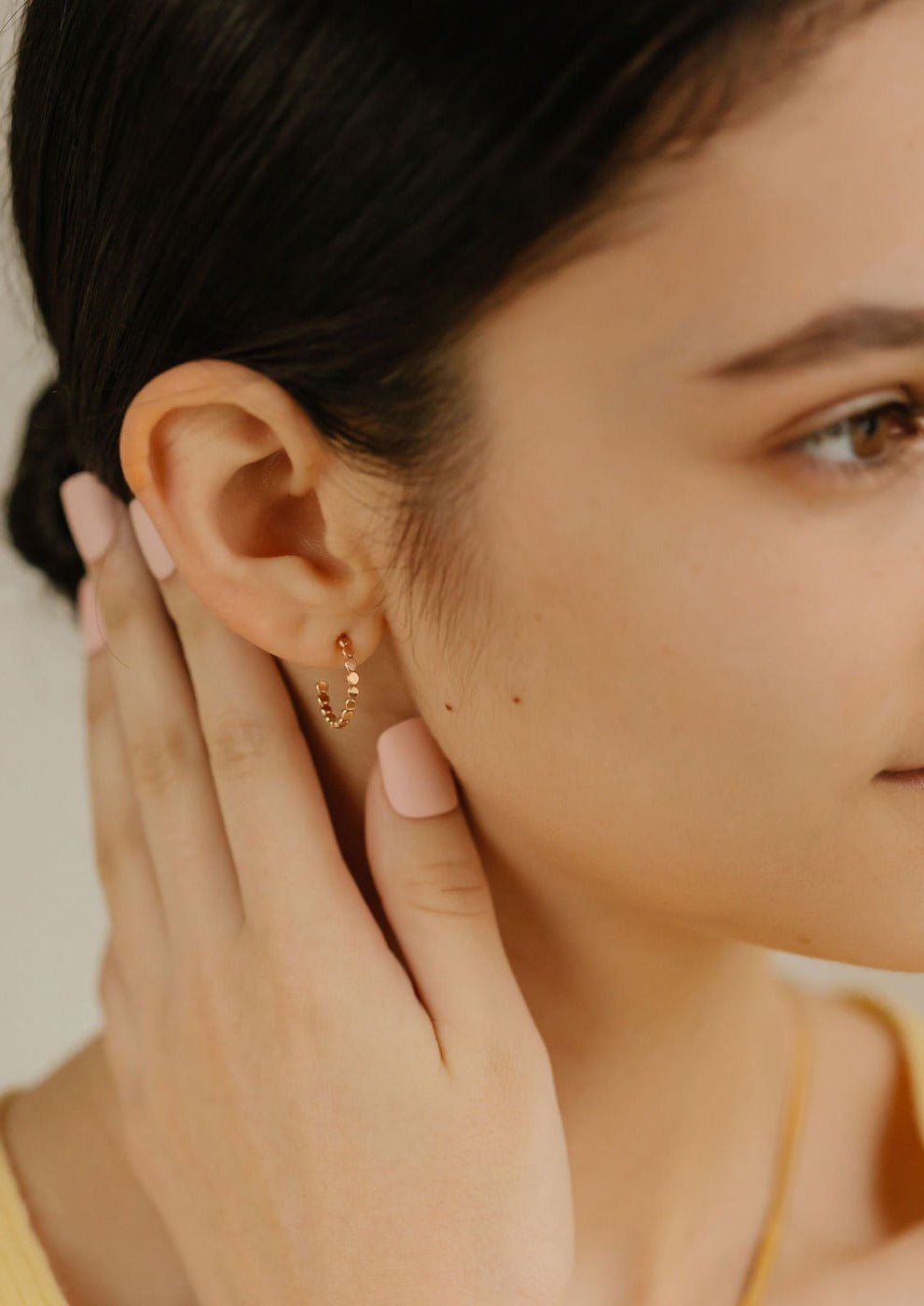  a woman is wearing gold filled flat bead hoop 