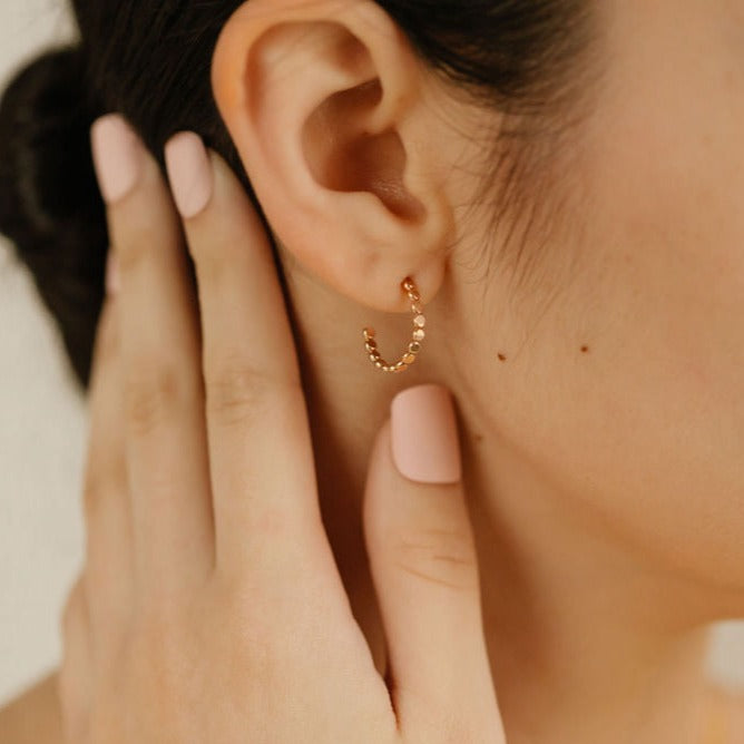 a woman is wearing gold hoop earrings made in canada