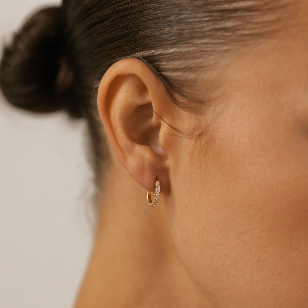 a woman is wearing gold vermeil pave hoops made in Canada