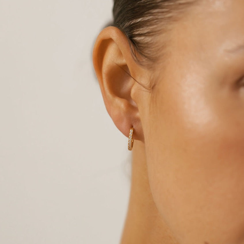 a woman is wearing tiny pave hoop earrings made in Canada