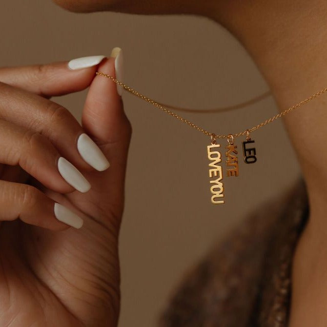 Woman is holding the name necklace with vertical pendants