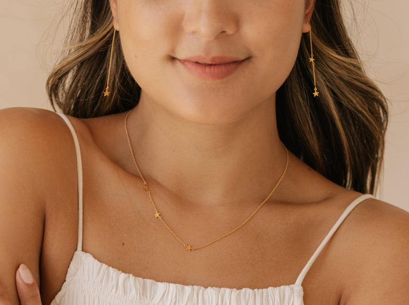 a woman is wearing a star necklace and earrings made in Edmonton, Calgary, Vancouver, and Toronto.