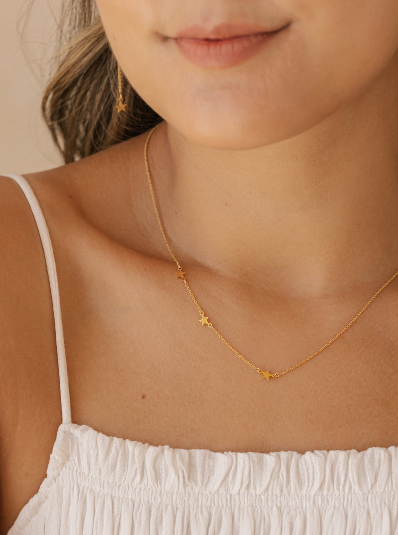 a woman is wearing a dainty star sideways heart necklace made in Canada