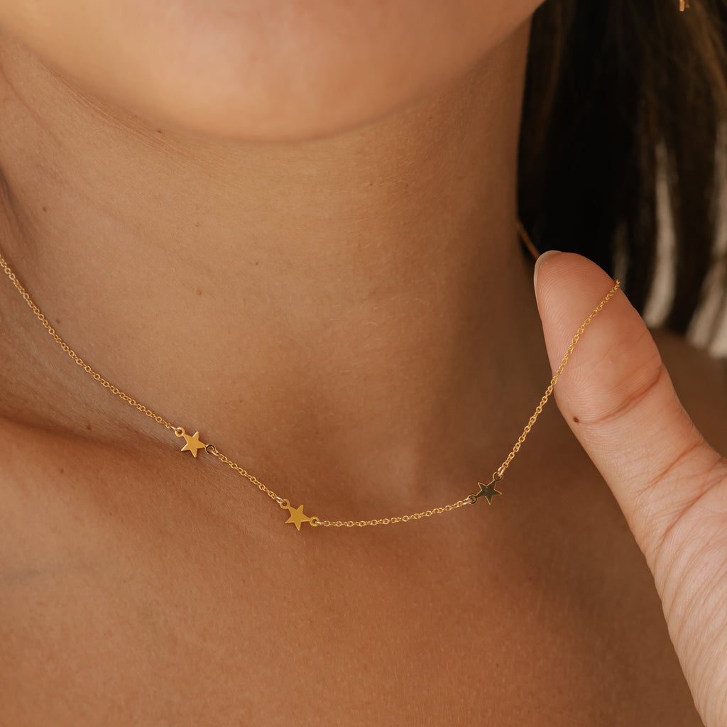 a woman is wearing gold vermeil star earrings made in Canada