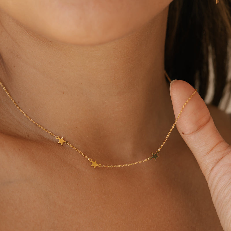 a woman is wearing gold vermeil star earrings made in Canada