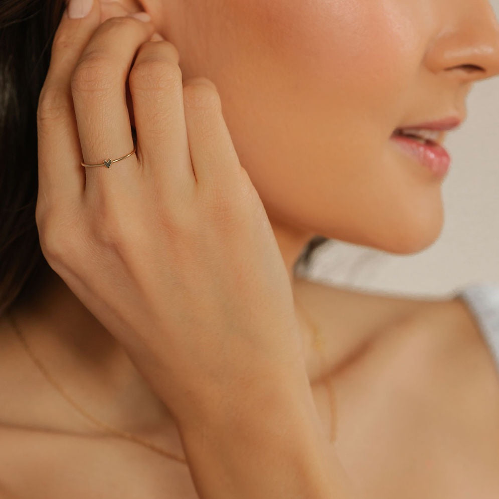 a woman is wearing gold heart stackable ring