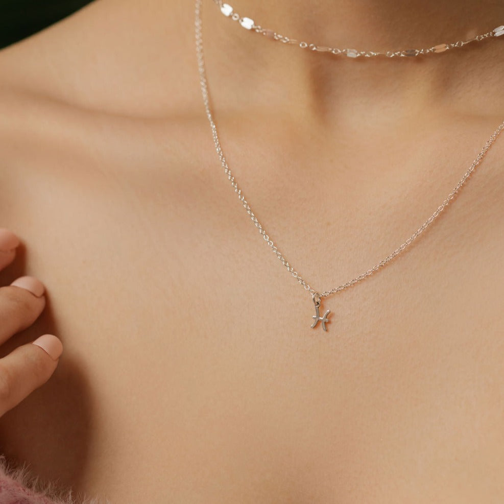 A model is wearing a zodiac Gemini sign pendant necklace