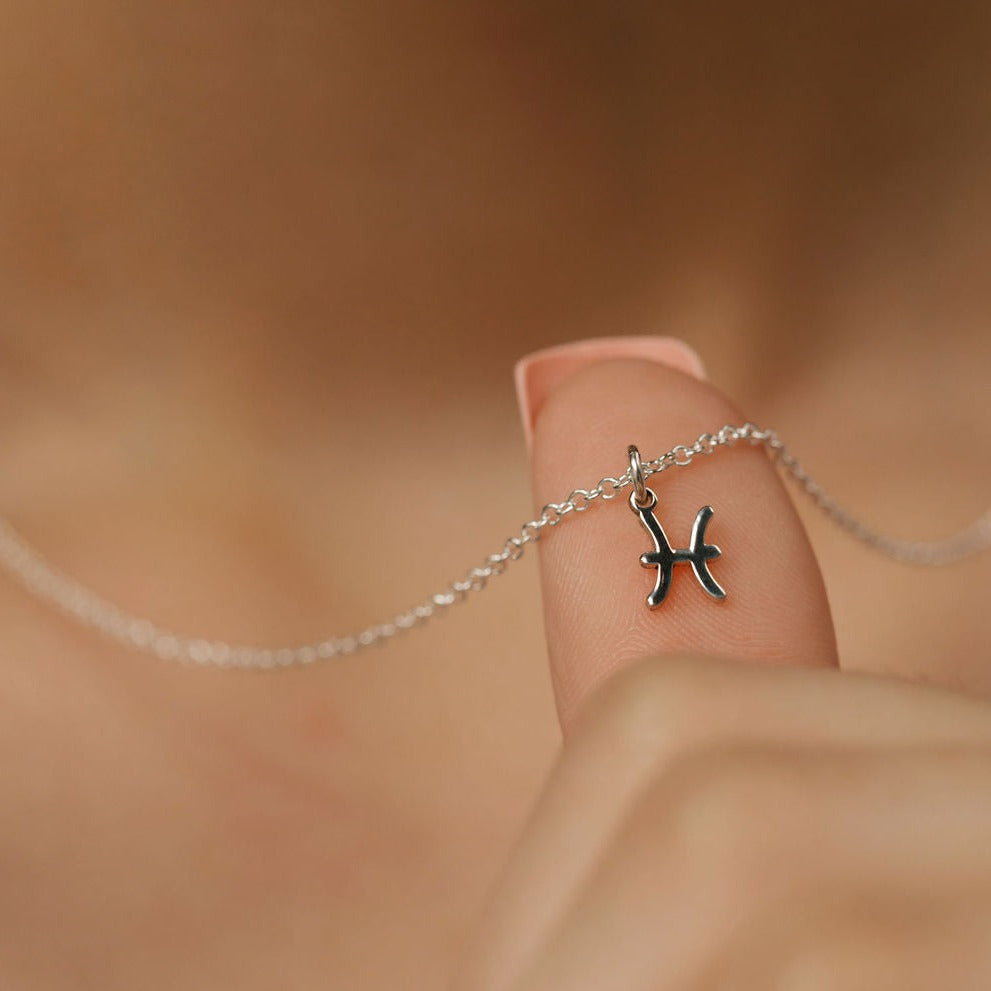 She is holding a silver gemini zodiac pendant.