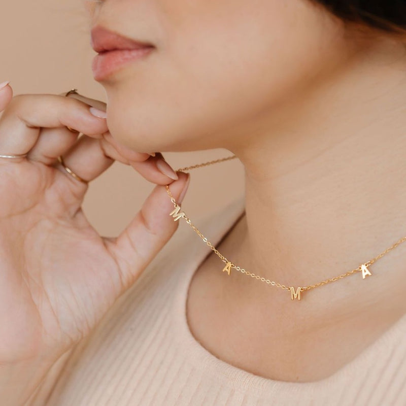 Woman wearing gold necklace that spells out MAMA