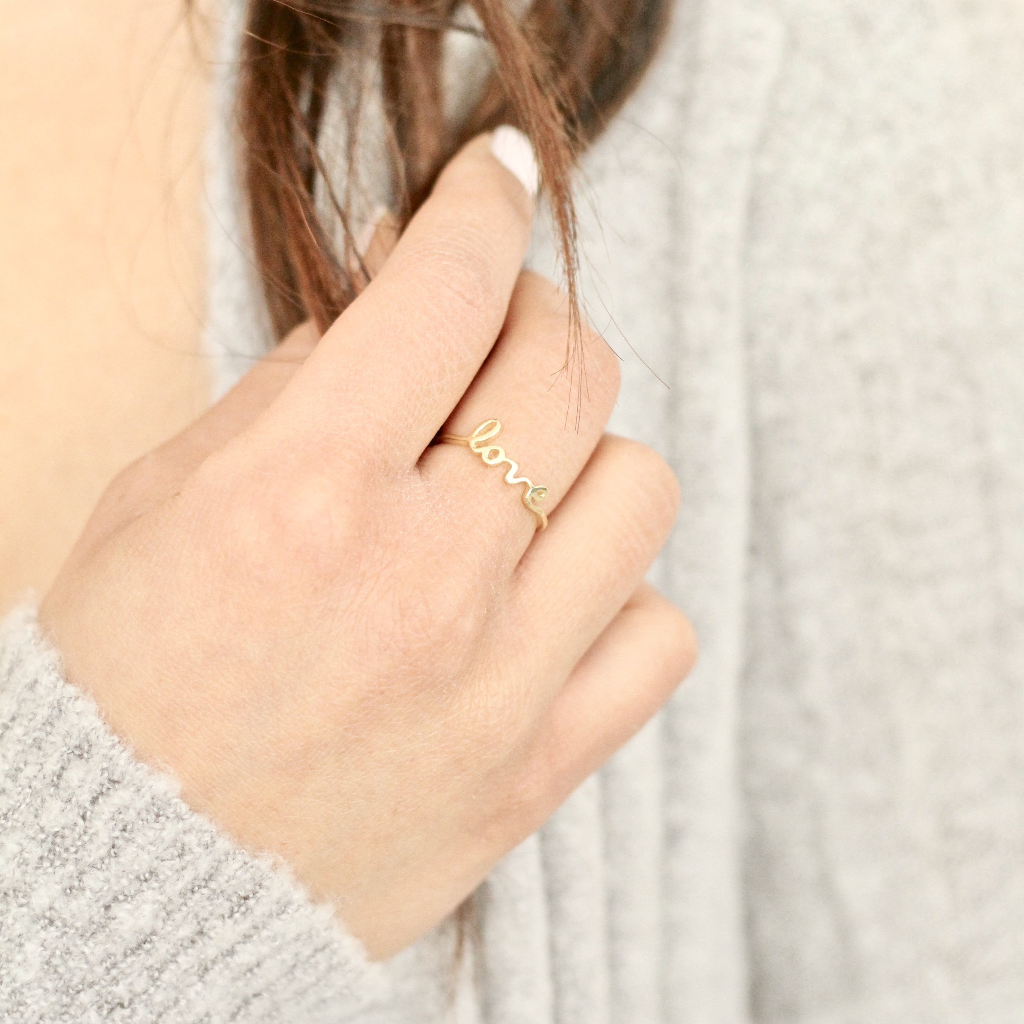 woman wearing handmade ring that says love made in canada 