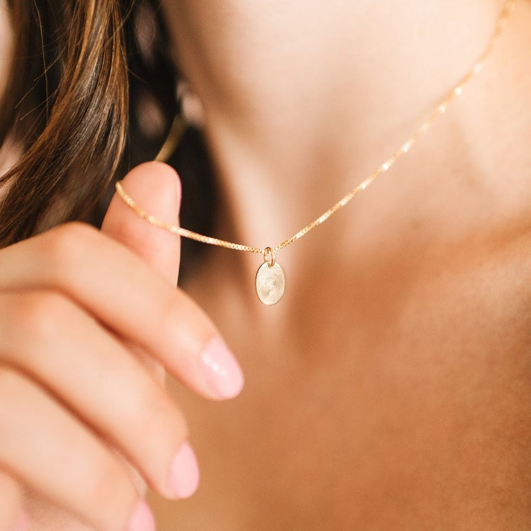 Woman wearing custom handmade gold fingerprint oval necklace