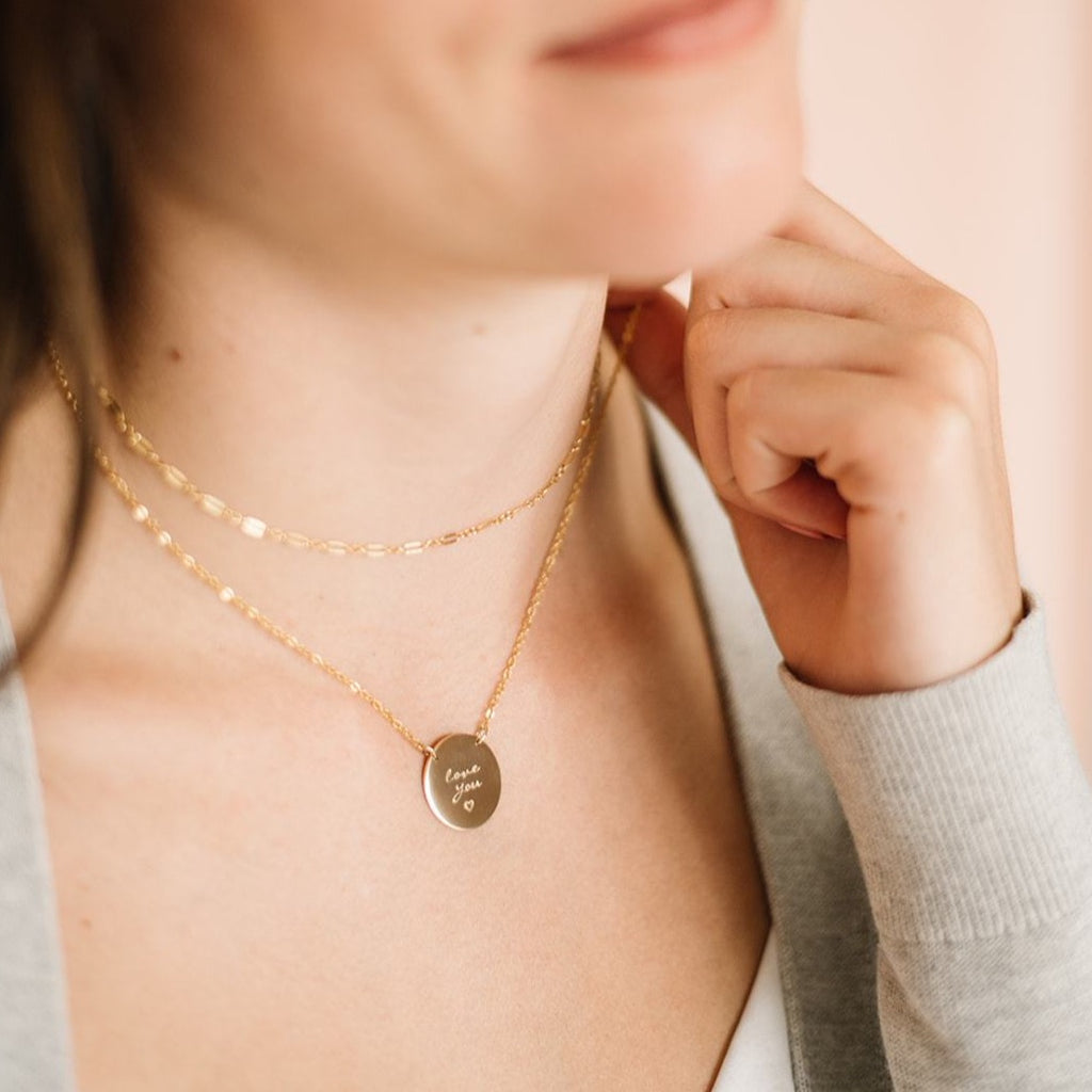 Woman wearing gold choker and gold custom handwriting coin necklace