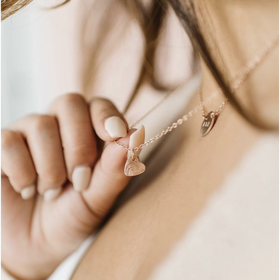 Woman wearing handmade custom rose gold tiny heart fingerprint necklace