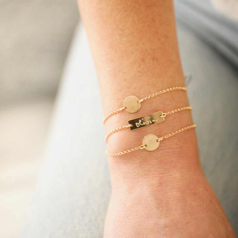Two custom handmade initial coin bracelets in gold and one handmade custom bar bracelet in gold