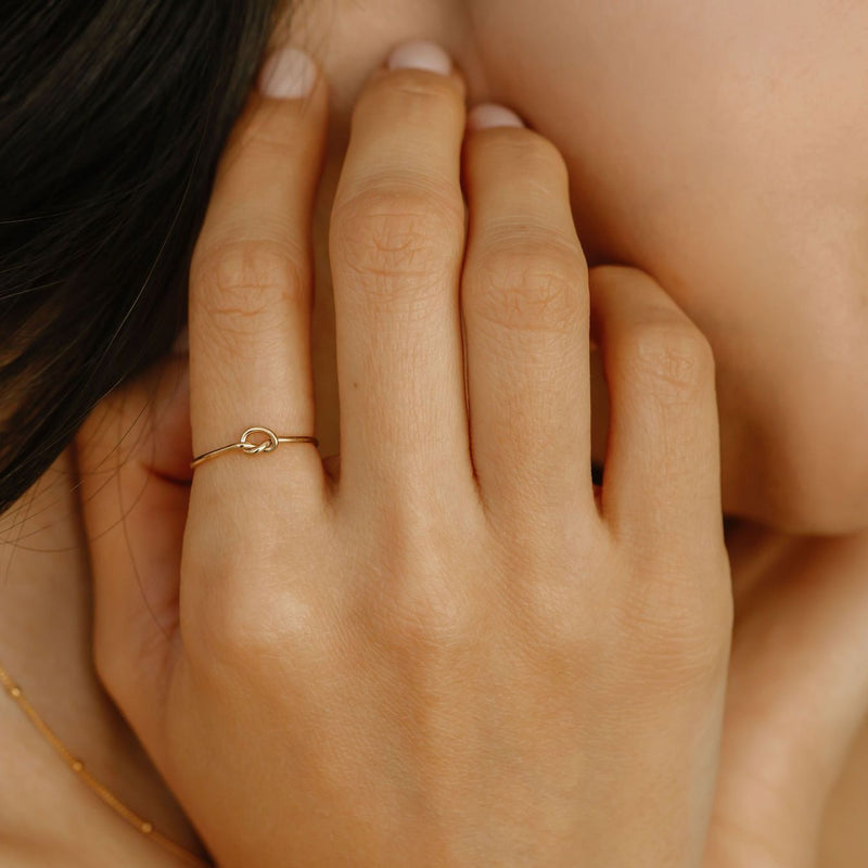 a woman is wearing a gold filled knot ring made in canada